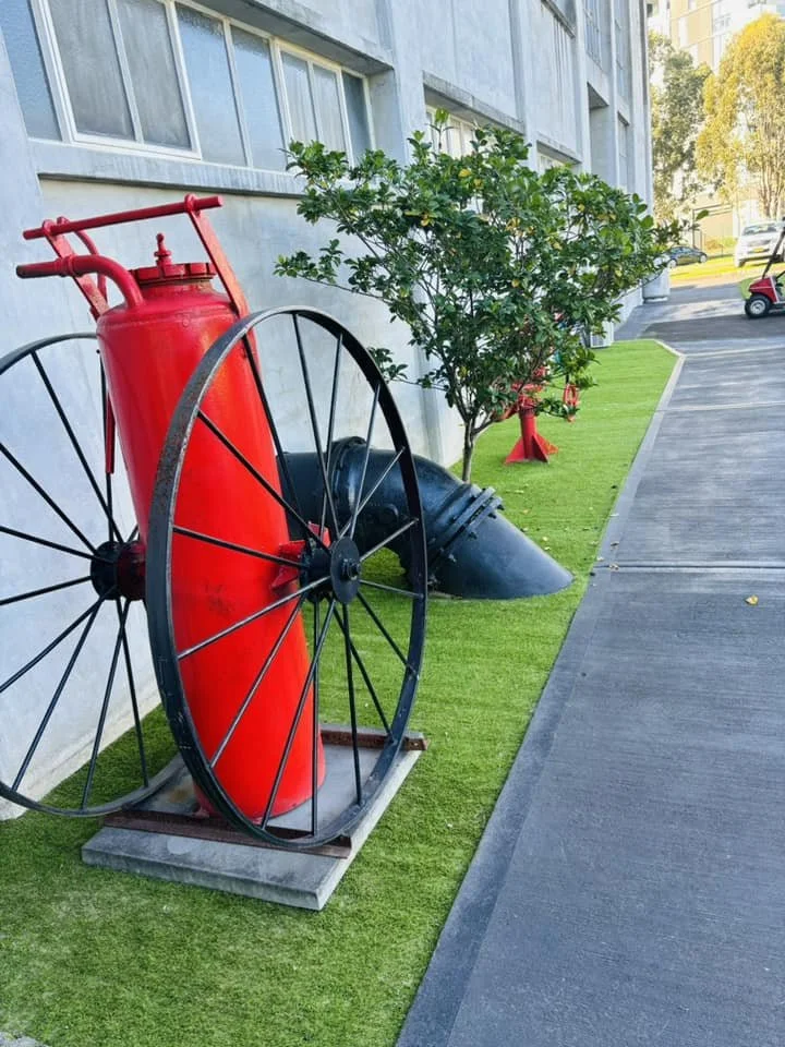 OneGrass synthetic turf professionally installed in a commercial area alongside vintage red firefighting equipment