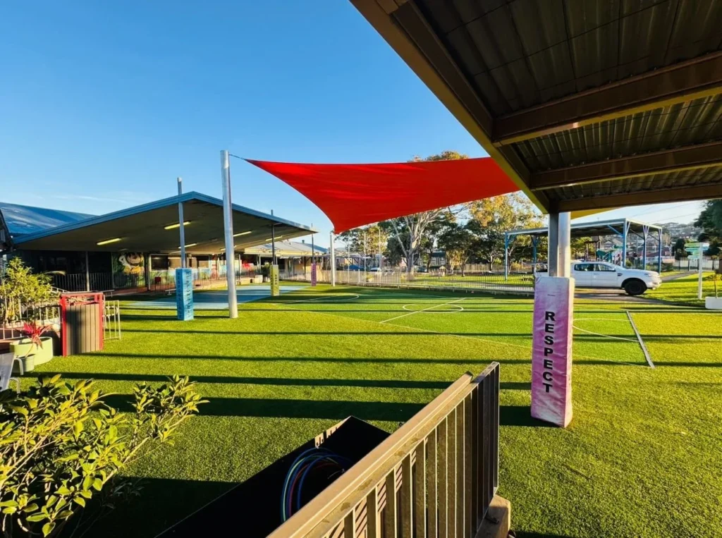 OneGrass multi-sport synthetic turf installed at a school playground featuring bright red shade sails