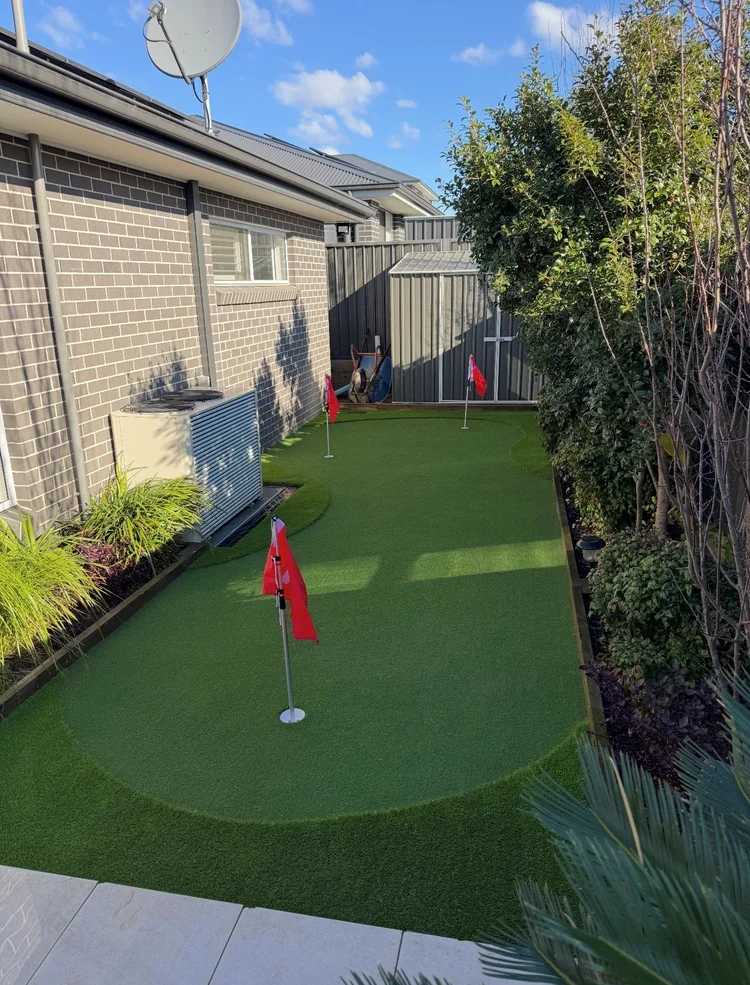 OneGrass synthetic turf installed in a residential backyard with red flags