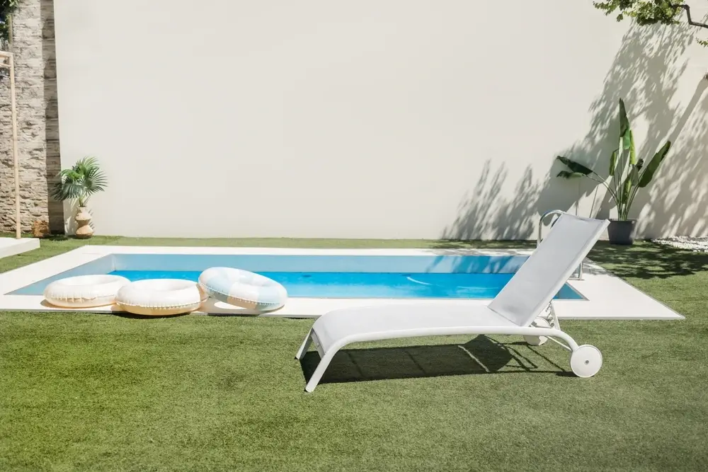 A pool deck view surrounded with OneGrass synthetic turf on a bright sunny day