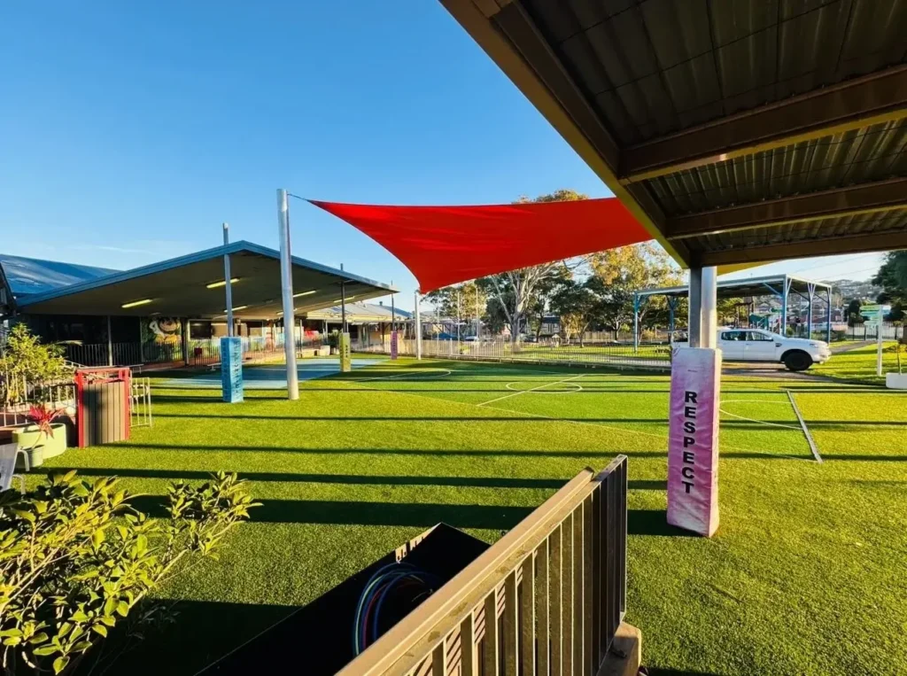OneGrass multi-sport synthetic turf installed at a school playground featuring bright red shade sails