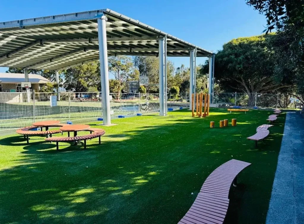 OneGrass synthetic grass creates a green, versatile surface for an undercover school play area with timber seating