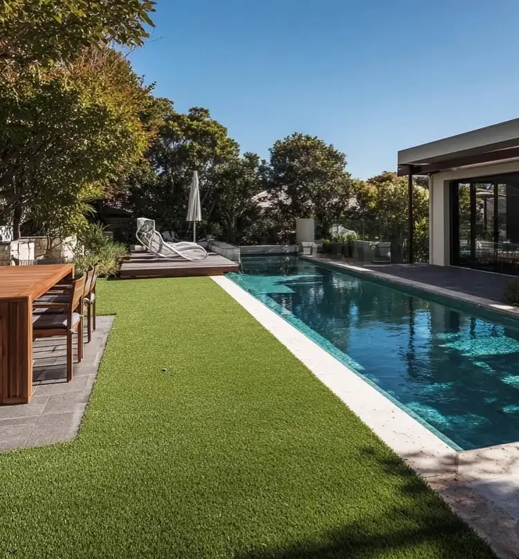 Lush OneGrass synthetic turf provides a clean, green lawn beside a modern lap pool and outdoor dining area