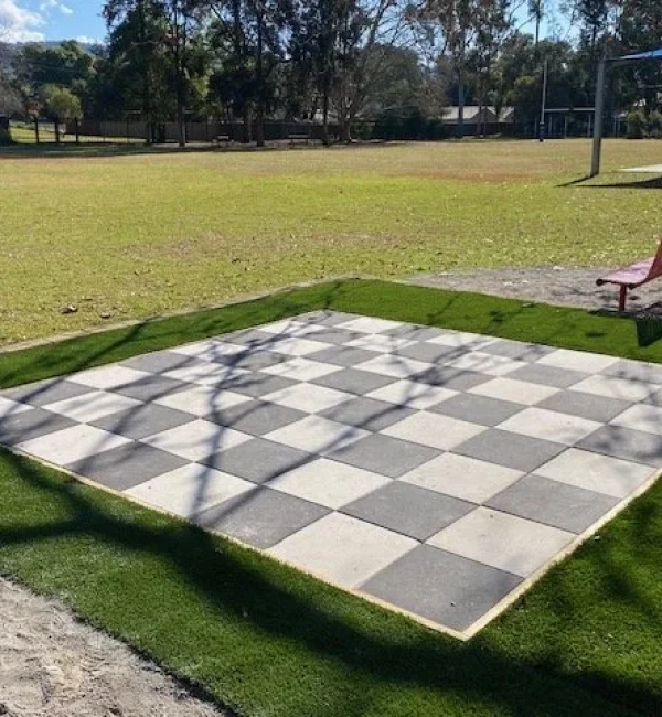 OneGrass synthetic turf borders a giant chessboard in a paved school courtyard area