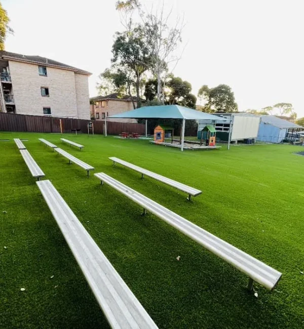 OneGrass durable artificial turf provides a clean, green surface beneath outdoor school seating and benches
