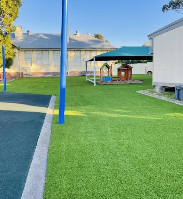 OneGrass synthetic turf provides a lush, low-maintenance lawn for a school playground with shade sails and play equipment