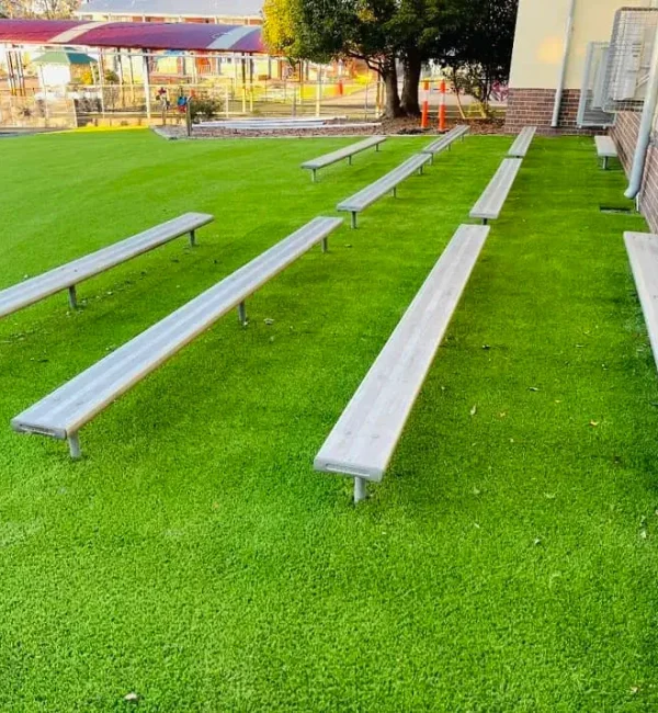 OneGrass durable artificial turf provides a clean, green surface beneath outdoor school seating and benches
