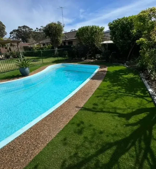 OneGrass synthetic turf provides a durable, low-maintenance lawn for a residential backyard pool with garden edging