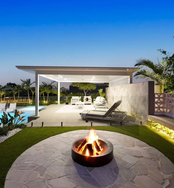 Luxury poolside entertaining area featuring OneGrass synthetic turf, a stone fire pit, and a modern white cabana