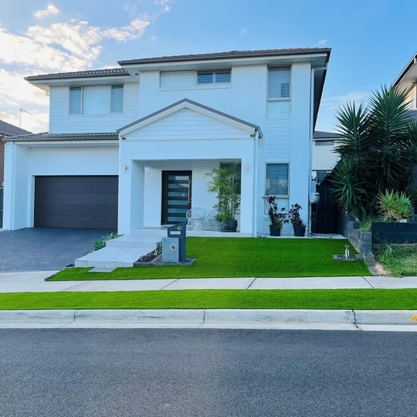 Lush OneGrass synthetic turf provides a neat, low-maintenance front lawn and nature strip for a modern white home