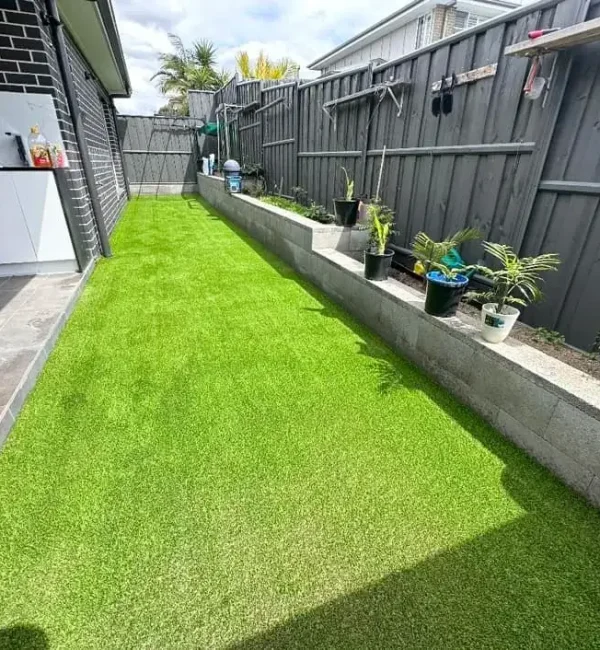 OneGrass synthetic turf creates a tidy, low-maintenance side yard lawn alongside a grey timber fence