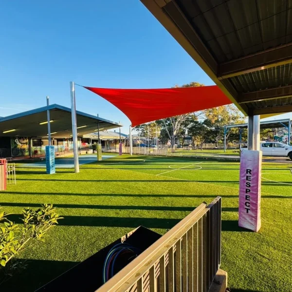 OneGrass multi-sport synthetic turf installed at a school playground featuring bright red shade sails