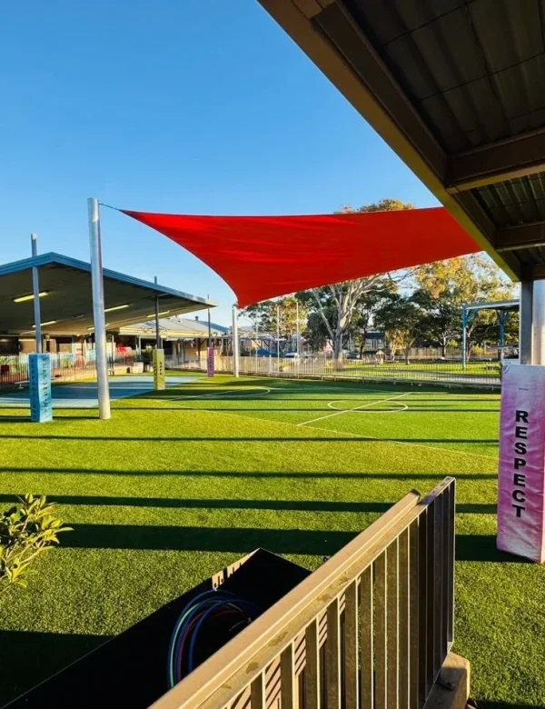 OneGrass multi-sport synthetic turf installed at a school playground featuring bright red shade sails