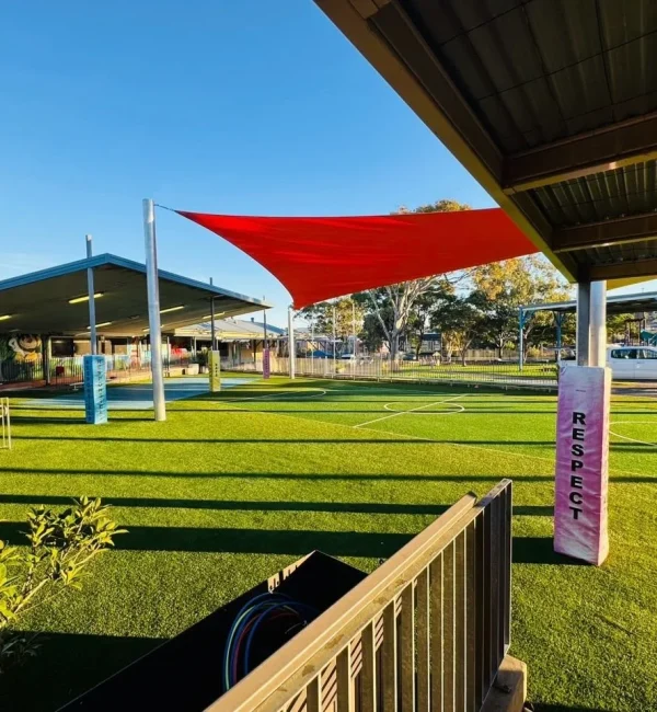 OneGrass multi-sport synthetic turf installed at a school playground featuring bright red shade sails