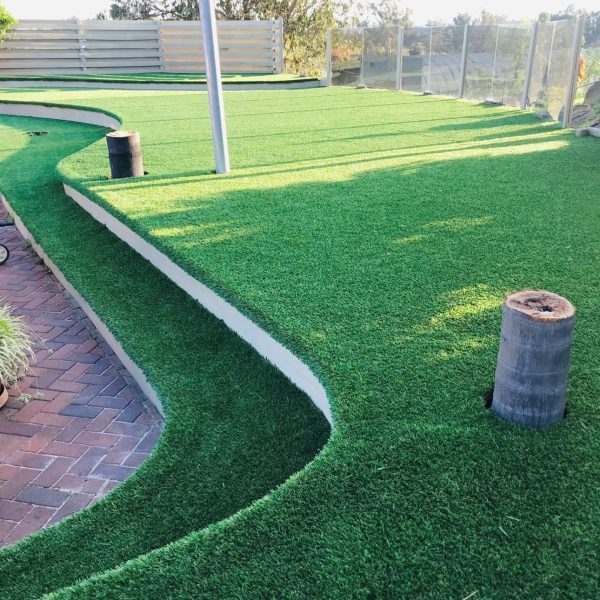 Tiered backyard transformation featuring OneGrass synthetic turf installed on curved, multi-level garden terraces