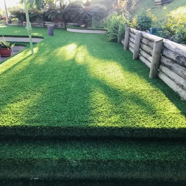 OneGrass synthetic turf creates seamless garden steps leading to a lush, tiered backyard lawn with timber retaining walls