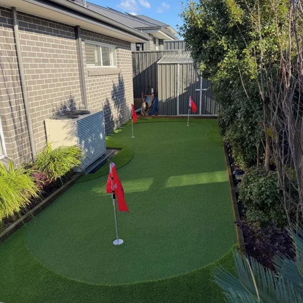OneGrass synthetic turf installed in a residential backyard with red flags
