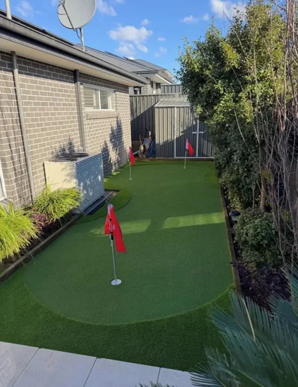 OneGrass synthetic turf installed in a residential backyard with red flags