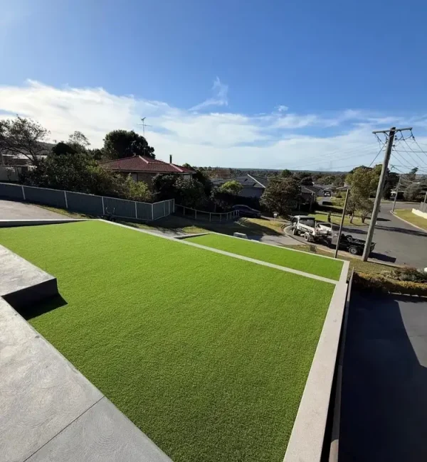 OneGrass synthetic turf provides a pristine, level front lawn for a modern home on a sloped suburban block