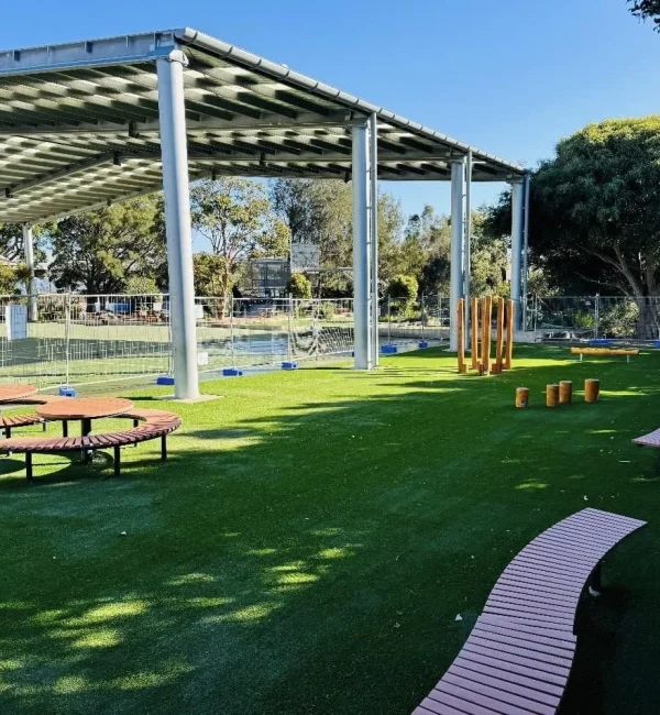 OneGrass premium synthetic turf provides a lush, durable lawn for a school play area with circular timber seating
