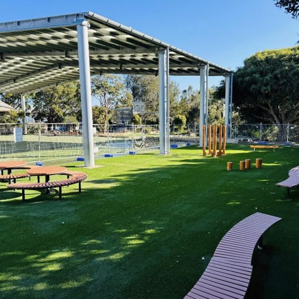 OneGrass synthetic grass creates a green, versatile surface for an undercover school play area with timber seating