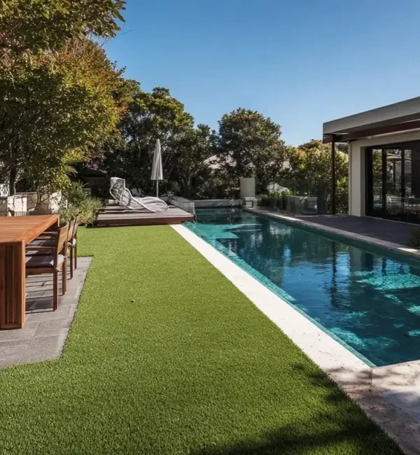 Lush OneGrass synthetic turf provides a clean, green lawn beside a modern lap pool and outdoor dining area