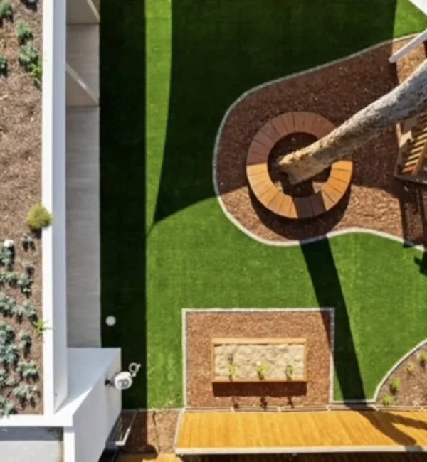 Aerial view of a OneGrass synthetic turf installed in a playground featuring integrated garden beds and circular tree seating
