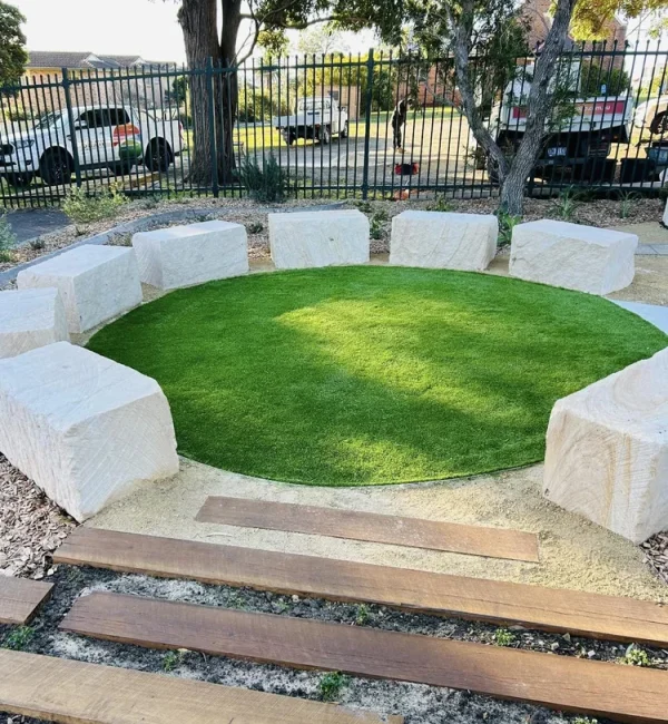 OneGrass premium synthetic turf provides a soft, circular lawn centrepiece surrounded by large sandstone block seating