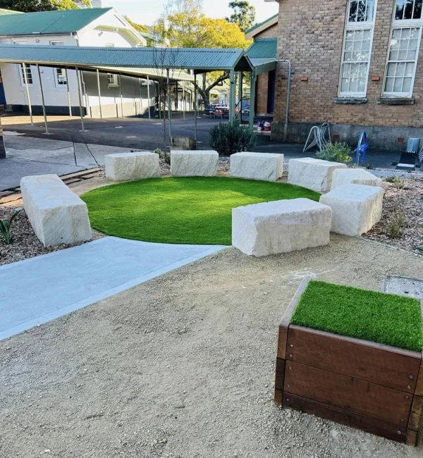 OneGrass premium synthetic turf provides a soft, circular lawn centrepiece surrounded by large sandstone block seating